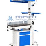 Baby warmer with blue overhead radiant heater head, crank handle for height adjustment, clear acrylic walls, blue side trays and a white cabinet base with drawer and door on castors