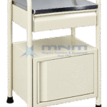 Cream hospital bedside locker built into a tubular steel frame with handles at both ends, a stainless steel top, one drawer and a cupboard, standing on four legs