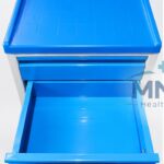 Hospital bedside cabinet trolley in blue and grey with two drawers pulled open and a moulded top tray with raised lip