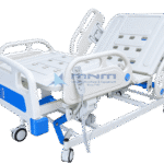 Electric 5 function ICU bed with white ABS head and foot boards, four ABS side rails, backrest raised and a handheld remote control on the side rail