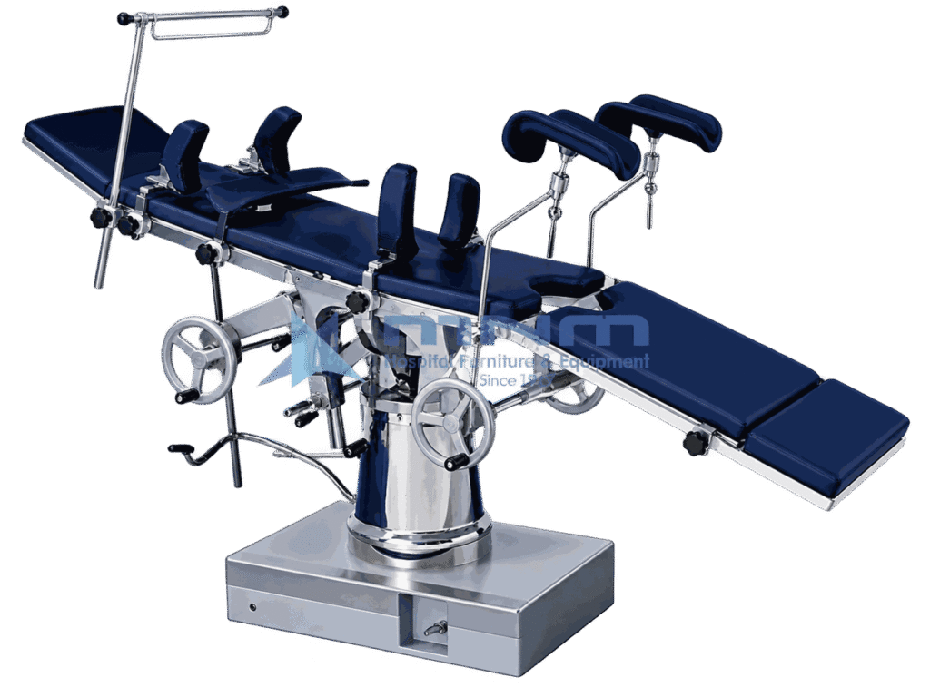 Operating table with navy upholstered top, padded stirrups and anaesthetic screen, controlled by twin handwheels on a conical chrome column and box base