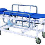 Stretcher trolley with a detachable blue canvas stretcher, pillow, restraint straps, grey drop-down side rails and a hand crank on a wheeled base